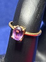 Close-up front view of the 14k yellow gold ring featuring oval purple amethyst stone mounted with four prongs on a thin band.