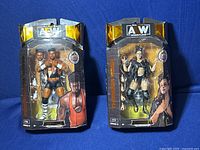 Two AEW wrestling figures Powerhouse Hobbs and Thunder Rosa in boxes with packaging and accessories visible