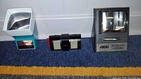 Three vintage slide viewers arranged side by side showing front view including lenses and brand logos