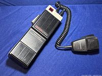 Full view of the Realistic TRC-210 walkie talkie showing rectangular speaker units and attached coiled cord leading to the microphone.