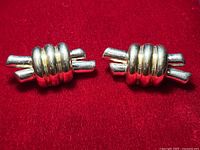Pair of vintage 925 sterling silver electroform clip-on earrings on red background showing twisted tube and ribbed ring band design.