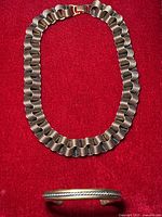 Copper coil link necklace laid flat on red background.