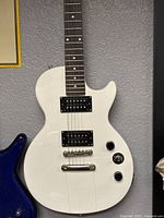 Front view of white Epiphone electric guitar showing overall body with visible cracks and two humbucker pickups.
