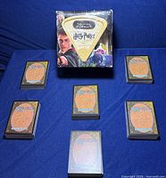 Harry Potter Trivial Pursuit game box with Magic the Gathering cards arranged around it on a blue surface.