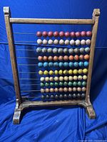 Front view of the antique Mongolian abacus showing wooden frame and nine rows of colorful beads on horizontal metal rods