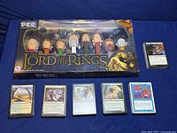 Boxed Lord of the Rings PEZ dispenser set with 7 character dispensers and a few Magic the Gathering cards laid out in front.