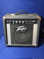 Front view of Peavey Audition 20 amplifier showing control panel, speaker grille, and power cord.