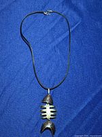 Full view of necklace with fish-shaped pendant on blue background.