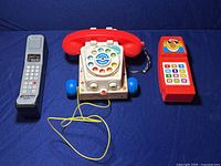 Three vintage toy phones on blue background, showing lot contents