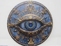 Front-facing photo of the round metal sign showing the detailed blue eye with golden decorative elements.