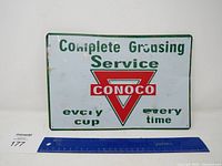 Full view of Conoco service metal sign with text and logo on white background