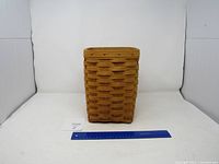 Front view of tall rectangular woven Longaberger basket with a blue ruler in front for size reference.