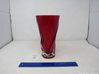Front view of the red glass vase with twisted swirl pattern and clear base, showing smooth top edge.