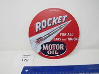 Front view of the Rocket Motor Oil round metal sign showing the rocket graphic and text.