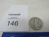 Photo showing the Standing Liberty silver half dollar coin next to a numbered paper and ruler for scale.