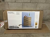 Box of Room Essentials 4-drawer dresser showing brand and product name.