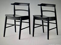 Front view of two black curved back wood dining chairs showing seat and backrest design
