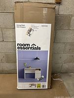 Full view of packaging box showing product brand, model name, and front image of desk in a minimal room setting.