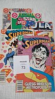 Five DC Comics comics arranged on a grey surface, visible titles include Superman, JLA, and annual editions.