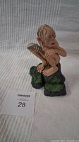 Smeagol figure crouching on rock base holding a fish, viewed from side showing detailed paint and pose.