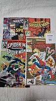 Five Marvel Spider-Man comic books laid out flat including Web of Spider-Man, Amazing Spider-Man, Peter Parker the Spectacular Spider-Man.