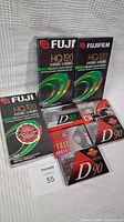 Photo of VHS and cassette tapes lot including Fuji HQ 120 VHS tapes, Maxell and TDK cassette tapes all in original packaging.