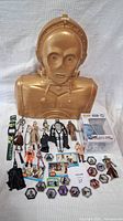Full lot showing large C-3PO case and array of Star Wars figures, badges, and other items arranged on white background