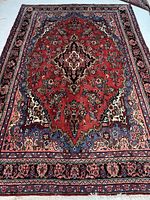 Full view of Persian Hamedan rug showing red field, central medallion, blue corners, dark blue borders.