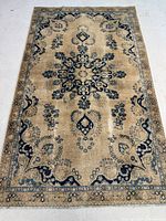 Full view of antique Persian rug laid flat showing overall beige and blue design with central medallion and border pattern.