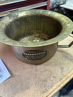 Antique brass railroad commode with visible patina and label on the side.