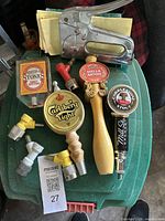 Top view of four beer tap handles and a staple gun on a green surface with connectors and a label