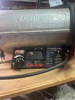 Close-up of the Coleman Heatmate branding and control panel with burner settings and instructions