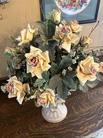 Top front angle of dry flower arrangement showing rose colors, foliage, and vase details.