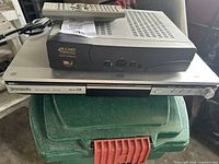 Panasonic DVD Player and Hughes Gold DIRECTV receiver stacked, remote on top