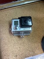 GoPro HERO3+ camera inside clear waterproof housing showing front display and lens