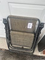 Folded view of gravity chair showing metal frame and woven fabric attached with lacing cords.