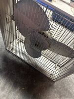 Front view of large vintage metal floor fan showing three blades and protective wire cage