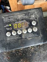 Close-up of the digital control panel showing buttons and LED display for temperature and time settings, with some dirt and wear visible on the surface.