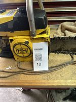 Close-up of the side of the yellow McCulloch chainsaw showing the metal emblem and part of the chain bar with MaxSold tag.