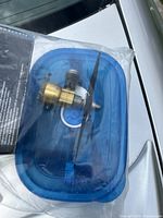 Small metallic airplane engine in plastic container, showing brass and steel components