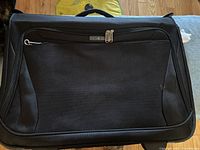 Front view of black Samsonite rolling wardrobe bag showing large front zippered pocket and Samsonite badge.