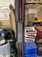 Full view of the 1969 Ford Thunderbird tail light assembly leaning vertically among other garage items, showing the full length and dual red taillight lenses.
