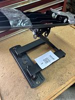 Photo showing the black metal TV wall mount bracket base and adjustable arm on a wooden surface.