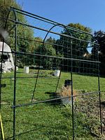 Full view of assembled metal arch tunnel plant support with green netting in garden setting