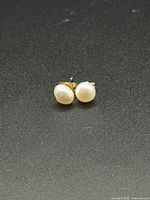 Pair of pearl stud earrings on dark background