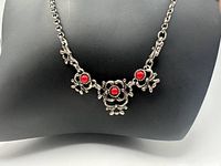 Full view of necklace on display bust showing design and red stones