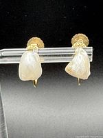 Front view of pearl earrings on display bar