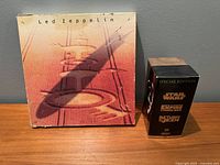 Photo of the Led Zeppelin CD box set and the Star Wars Trilogy VHS box set side by side on a wooden surface.