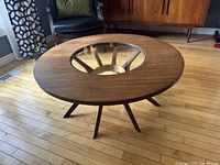 Front three-quarter view showing round walnut veneer top and circular glass insert.