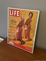 Framed Life Magazine cover on table with Marilyn Monroe and Jane Russell in red dresses